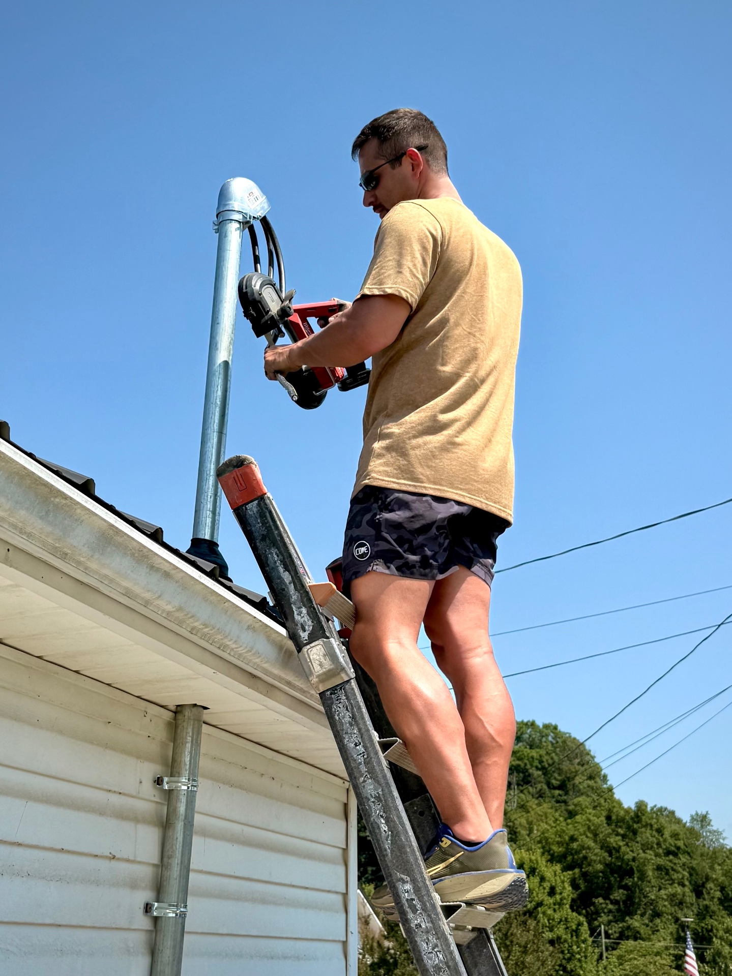 Ryan Trent installing a service mast and weatherhead from a ladder on an East Tennessee home