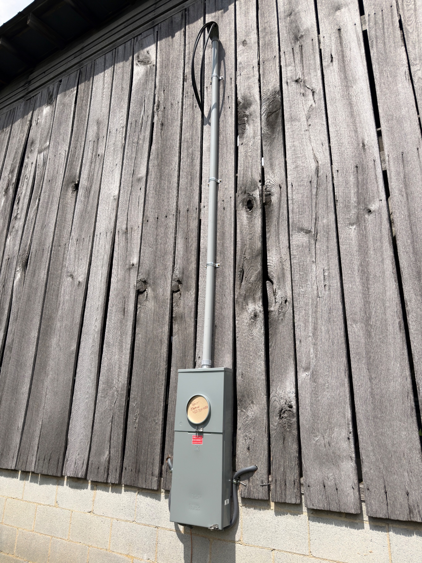 New 200-amp meter base and service mast installed on a weathered wood barn in Goshen Valley near Church Hill, TN